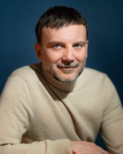 Beżowy golf na niebieskim tle, widać spokojnie leżącą dłoń